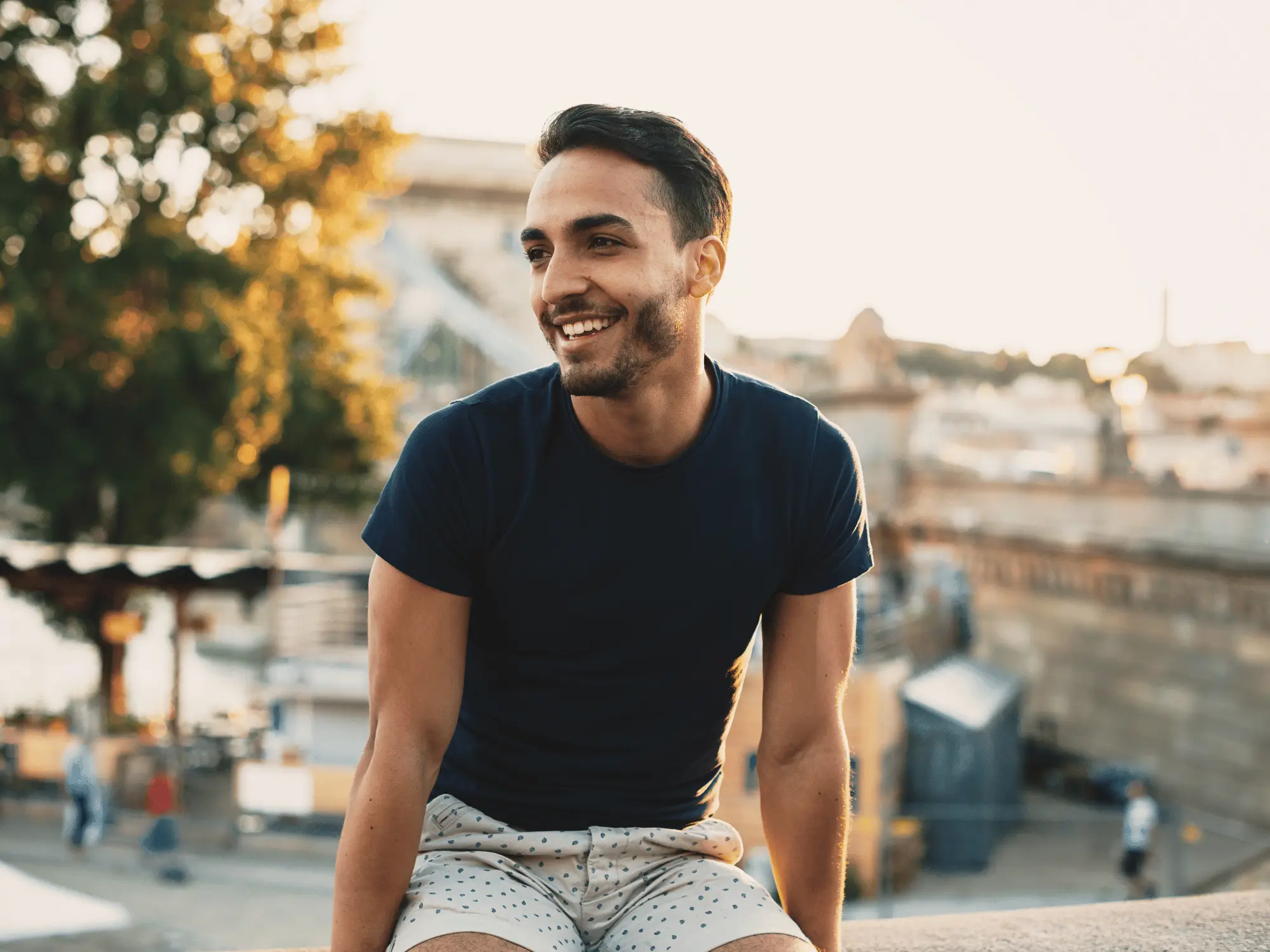 Smiling man in a navy t-shirt sitting outdoors at golden hour